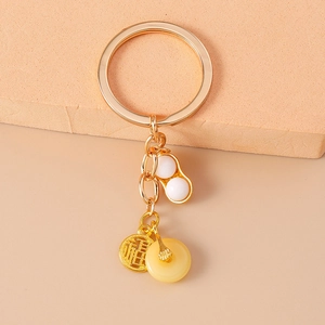 Détail d'un porte-clés cacahuète doré avec pendentif Fú et anneau en simili jade
