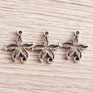 Three starfish-shaped antique silver charms with spiral textures and dual connection rings