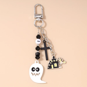 Close-up of Halloween keychain featuring white ghost charm, haunted house, and black cross