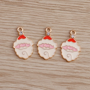 Detail of three Santa Claus charms with red enamel and rhinestones on wood background