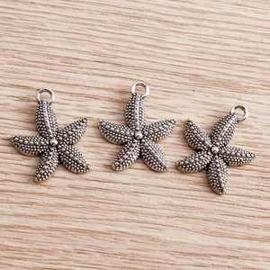Macro view of vintage silver starfish charms with detailed textured dots for DIY jewelry