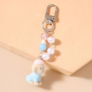 Detail of plush dog keychain with blue sweater, pink hat and pearl beaded chain