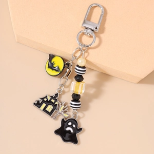 Detailed close-up of a Halloween keychain with ghost, bat, moon, and haunted house charms