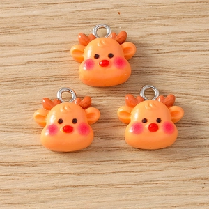 Detailed view of three orange reindeer pendants with silver metal rings for DIY jewelry