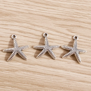 Detailed view of silver alloy starfish charms with dot textures for DIY jewelry making