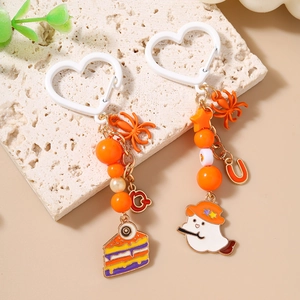 Halloween keychain with ghost and cupcake charms, orange beads and spider on stone surface