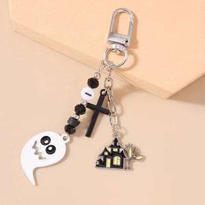 Detail of Halloween keychain with white ghost, black cross and haunted house charms