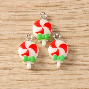 Three red and white candy lollipop pendants with green bows on a light wooden surface