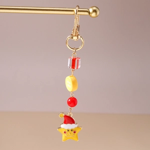 Close-up of Christmas star keychain with red hat, beads and golden metal clasp hanging