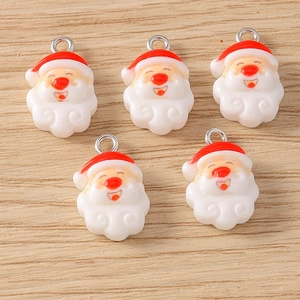 Close-up of five Santa Claus enamel pendants for DIY jewelry on light wood background