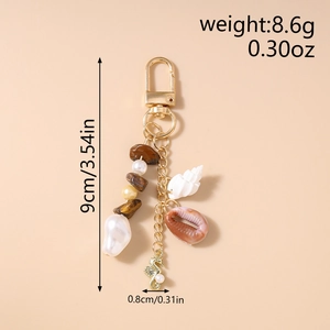 Detail showing shell and pearl beads on a golden keychain with product dimensions