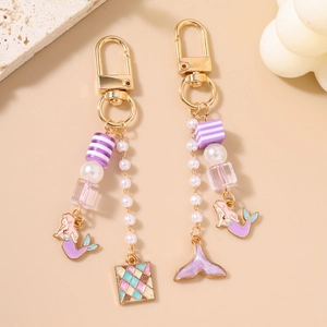 Porte-clés sirène élégant avec perles violettes et breloques émaillées dorées sur pierre