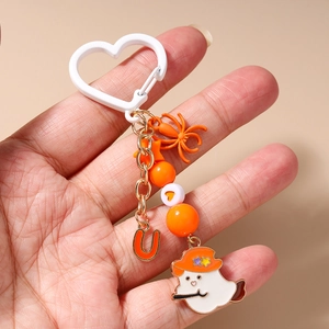 Detail of Halloween beaded keychain with orange ghost and heart charms held in hand