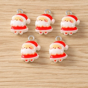 Macro view of five cartoon Santa Claus resin charms with silver metal rings on wood