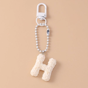 Detail of cream white H-letter keychain featuring a delicate 3D rose flower texture