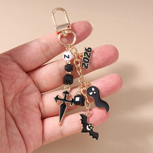 Detailed view of Halloween keychain with bat ghost charms and 2026 tag held in hand