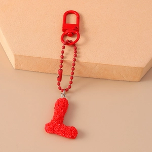 Macro detail of red letter L keychain charm with 3D miniature rose flower textures