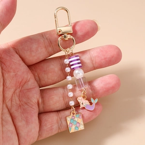 Détails d'un porte-clés sirène avec perles blanches et fermoir doré en alliage