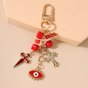 Detail of red enamel cross pendants and 2026 tag on a gold Halloween keychain