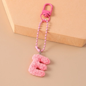 Detail shot of a pink floral letter E keychain with rose texture and metal D-ring clasp
