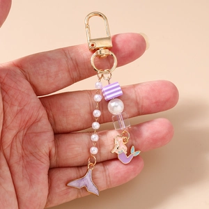Détail du porte-clés sirène avec émail violet, métal doré et perles blanches