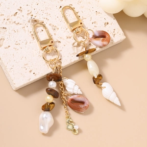 Close-up of golden starfish keychain with ocean shells, white pearls and seahorse charm