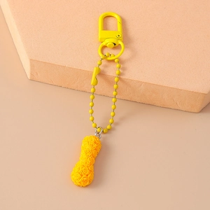 Detail of yellow peanut shaped keychain with floral rose texture on a peach block