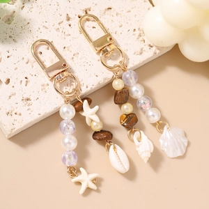 Detail of beaded starfish keychain featuring white pearls and ocean shell charms