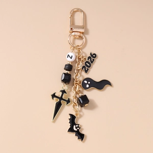 Detail of gothic beaded keychain with gold cross, black bat and white ghost charms
