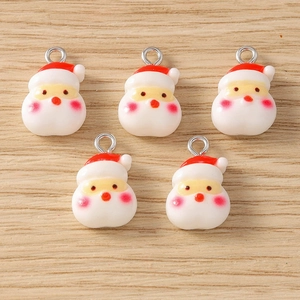 Detail view of 5 cute cartoon Santa Claus charms with metal loops on wood background