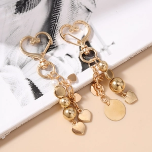 Porte-clés cœur doré avec perles métalliques et breloque perle sur magazine de mode