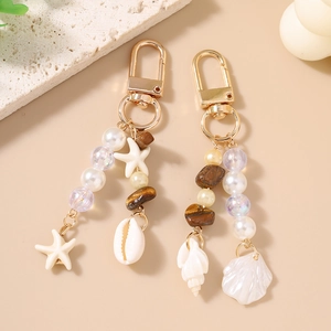 Starfish and shell beaded keychains with pearls and natural stones on beige background