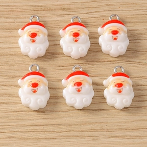 Detailed view of six Santa Claus resin pendants with metal rings on wood background