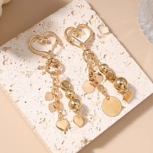 Porte-clés doré en forme de cœur avec perles et breloques sur socle en pierre