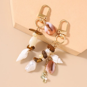 Macro shot of seashell and seahorse keychain charms with pearls and tiger eye stones