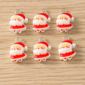 Detailed view of six Santa Claus resin charms for DIY jewelry on light wood surface