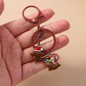 Detail of Christmas keychain with Santa on sleigh and smiling star charm held by hand