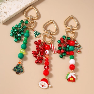 Three festive Christmas keychains with bells, Santa, and tree charms on gold heart clips