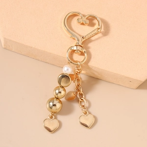 Vue détaillée du mousqueton coeur doré avec des perles et des pendentifs coeur
