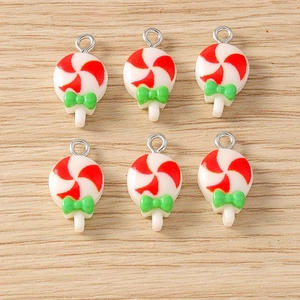 Lollipop charms for DIY jewelry with red spirals and green bows on wooden surface