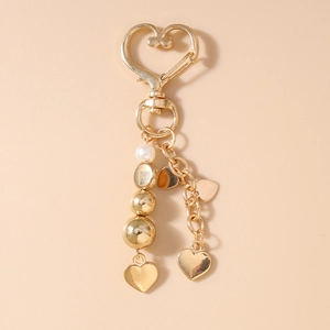 Vue détaillée d'un porte-clés cœur doré avec pendentifs en perles et breloques en cœur