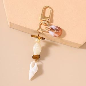 Detail of ocean-themed keychain featuring natural cowrie shells and tiger eye beads