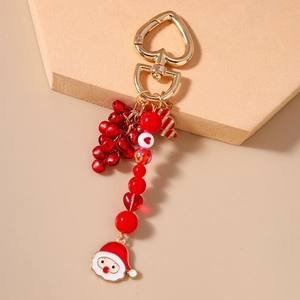 Close-up of Christmas keychain with red beads, bells, and Santa Claus enamel pendant