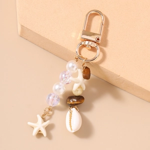 Detail of beaded starfish keychain featuring white pearls, shells, and gold metal clasp