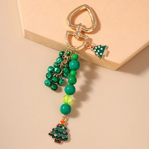 Detail view of Christmas keychain with green beads, golden bells, and enamel tree charms