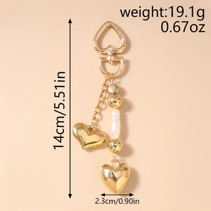 Vue détaillée du porte-clés cœur avec pendentifs dorés, perle et dimensions indiquées
