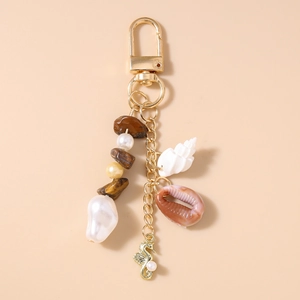 Detail of beach keychain with golden seahorse charm, tiger eye stones and natural shells