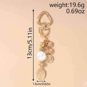 Close-up of golden heart clasp keychain with pearls, tree of life and coin charms