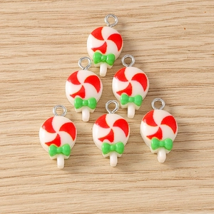 Close-up of red and white striped lollipop charms with green bows for DIY jewelry making