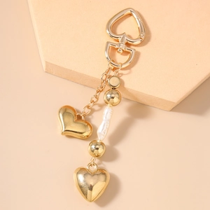 Détail d'un porte-clés coeur doré avec perle baroque et perles métalliques de décor